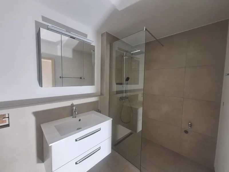 Helles Badezimmer mit Glasdusche und Waschtischmöbel